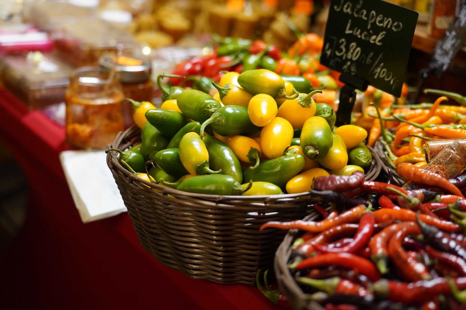 Colorful jalapeño and chili peppers at a market stall — the whole peppers Fierro Fire starts with