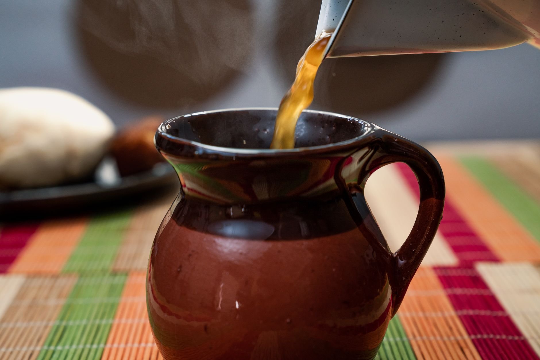 Liquid pouring from a kettle into a ceramic jug — the careful, deliberate process behind every Fierro Fire sauce
